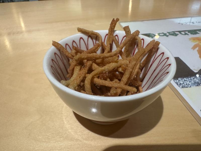 そば処河内屋のお通し、赤い線模様の小鉢に盛られたカリッと揚げたそば揚げ
