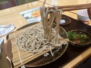 そば処河内屋の十割そばを箸で持ち上げた様子、やや太めで平たい手打ちの麺